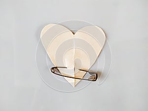 Paper heart with metal safety pin on white background