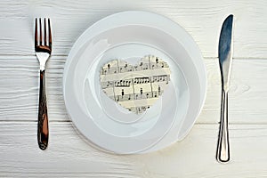Paper heart with musical notes on white plate.