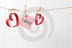 Paper hearts and LOVE hanging on the line on white background