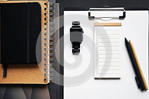 Paper holder next to folders, notepads, pens, calendar, wristwatch and wired headphones