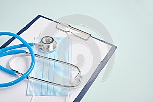 paper holder with white sheets, medical stethoscope, pills on a blue background,, copy space