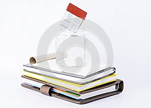 Paper home into empty glass on books stack