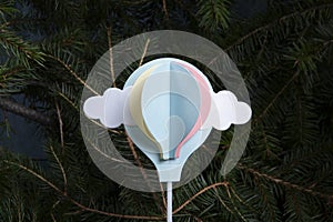 paper hot-air balloon, initially a cake decoration, flying up from a fir-tree forest photo