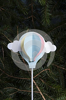 paper hot-air balloon, initially a cake decoration, flying up from a fir-tree forest photo