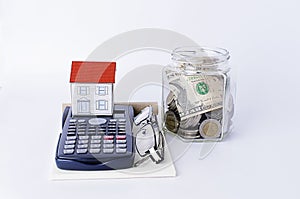 Paper house with calculator and glasses and bottles saving money