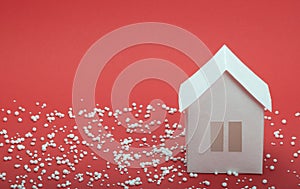 Paper house in snow on red background