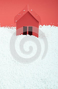 Paper house in snow on red background