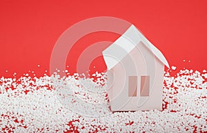 Paper house in snow on red background