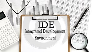 Paper with IDE INTEGRATED DEVELOPMENT ENVIRONMENT a table on charts, business concept
