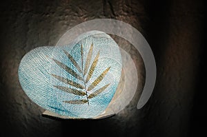 Paper lamp heart blue with dry leaf on in the dark