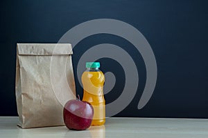 Paper lunch bag on desk with apple