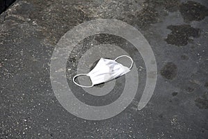 Paper Medical Face Mask used to protect against Coronavirus thrown on the ground in a parking lot. Abandoned coronavirus personal