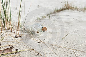 Paper Message in a glass bottle with a cork on the sand