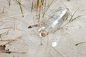 Paper Message in a glass bottle with a cork on the sand