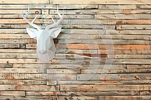 Paper moose head hanging on the wall with a view of the wooden boards. Copy space.