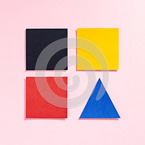Paper multicolored squares and a triangle on a pink background