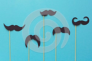Paper mustache on booth props on blue paper background. Cut out style. Movember concept.