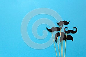 Paper mustache on booth props on blue paper background. Cut out style. Movember concept. photo