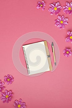 Paper note with flowers on pink background. Top view.