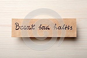 Paper note with phrase Break Bad Habits on white wooden table, top view