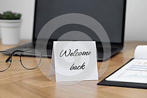 Paper note with phrase Welcome Back on office desk photo