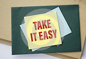 Paper note with TAKE IT EASY written on black