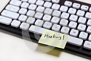 Paper note to remind meeting on keyboard