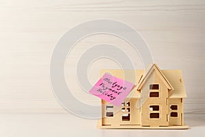 Paper note with words Mortgage Payment Holiday and house model on white wooden table, space for text