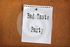 Paper note written with BAD TASTE PARTY inscription on cork board