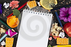 Paper notebook with blank pages, crumpled paper balls and crayons, scattered foods on wooden background