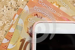 Paper notes from Canada. Dollar. Blank cel phone screen and bills on marble