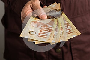 Paper notes from Canada. Dollar. Front view of old woman`s hand handling bills