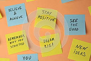 Paper notes with life-affirming phrases on pale orange background