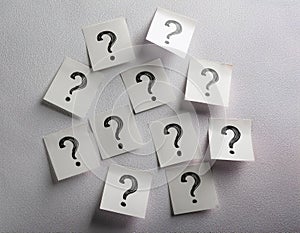 Paper notes with question marks on white background, flat lay. Space for text