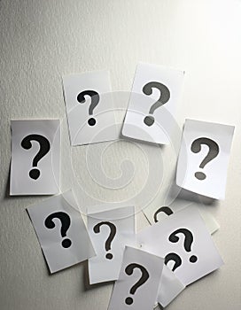 Paper notes with question marks on white background, flat lay. Space for text