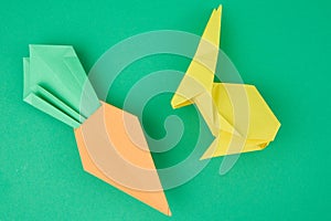 Paper origami rabbit and carrot on green background