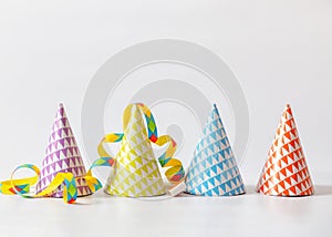 Paper party birthday hats and streamers on white background with copy space