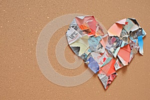 a paper patchwork heart made from magazine cutouts on a cork board