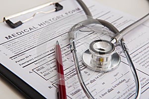 On paper patient health history medical questionnaire form lie doctor diagnostic tools - stethoscope and thermometer. Process of i