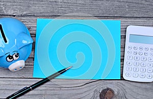 Paper with pen and piggybank on wooden table