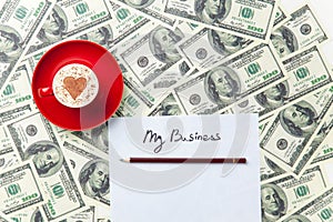 Paper, pencil, cup and dollars lying on the table