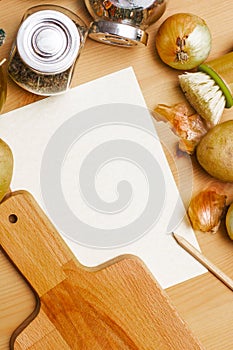 Paper, pencil, jug of olive oil, potatoes, onion, cutting board and spices