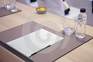 Paper, pencil, water bottle, glass on the table in the seminar room