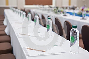 Paper, pencil, water bottle, glass on the table in seminar room background