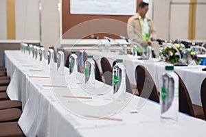 Paper, pencil, water bottle, glass on the table in seminar room background