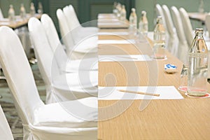 Paper, pencil, water bottle, glass on the table in the seminar room background