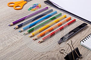 Paper, pencils, brush, green apple on wooden table