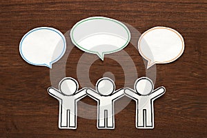 Paper people with colorful blank dialog speech bubbles on brown wood. Communication concept.