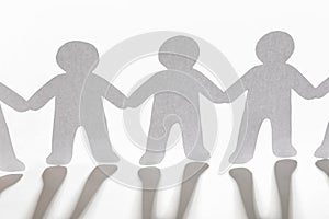 Paper people holding hands on light background