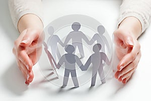 Paper people surrounded by hands in gesture of protection. Concept of insurance photo